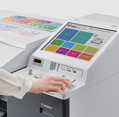 セブン‐イレブン店内でマルチコピー機を操作。QRコードをかざすか、画面から「プリント」→「ネットプリント」を選び、プリント予約番号を入力する。画面の案内にしたがって操作。