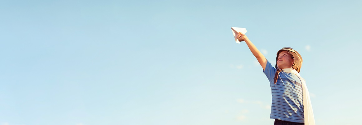 A boy flying a paper airplane
