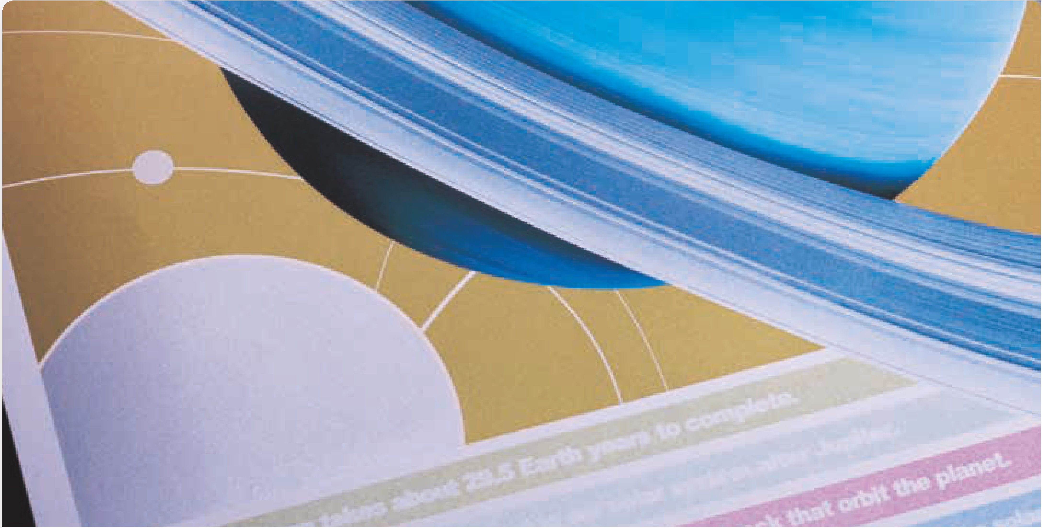 Close-up of printed pages featuring a planetary design with blue rings and gold background, showcasing metallic effects for premium print quality.