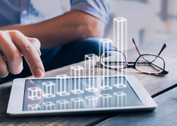 A person interacting with a digital tablet displaying an upward bar chart, with glasses resting on the table nearby.