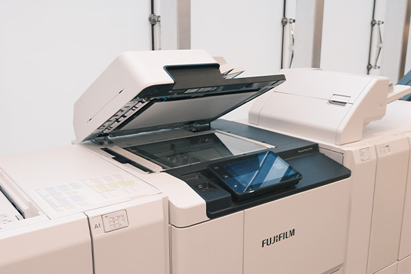 Staff pressing button on printer to start digital printing by Fujifilm Business Innovation